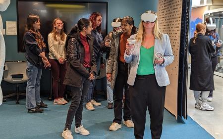 A person wearing virtual reality goggles in a room full of people.