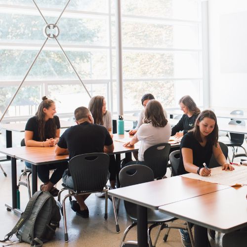 Students collaborate around a classroom table in a light, airy classroom.