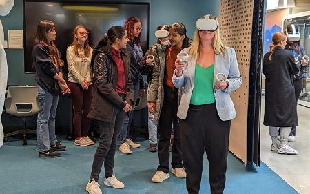 A person wearing virtual reality goggles in a room full of people.
