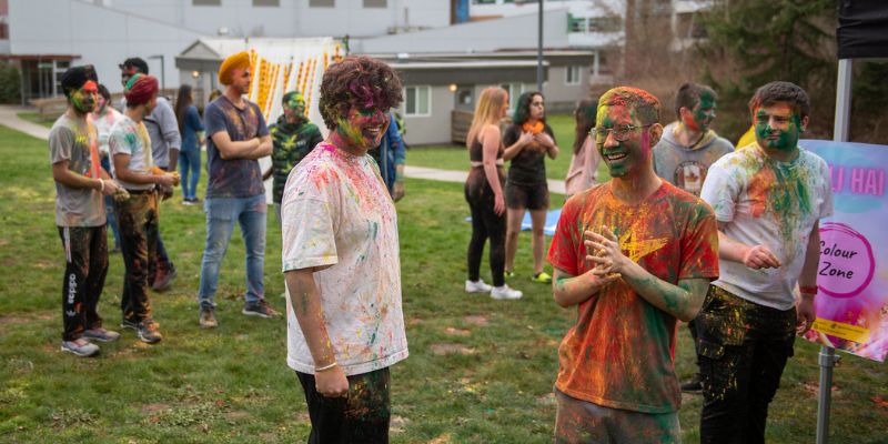 Students laughing and covered with colourful powder for Holi