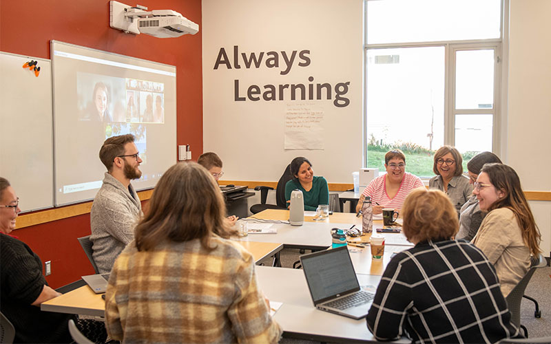 Group of people sitting around a conference table in a meeting room with 