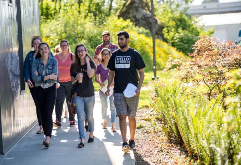 A group of students smiling and chatting while they walk together on UFV's campus.
