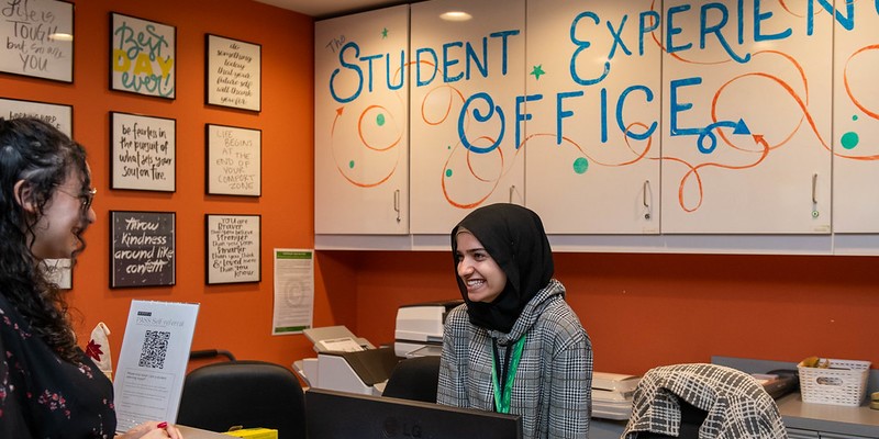 A smiling lounge leader assists a visitor