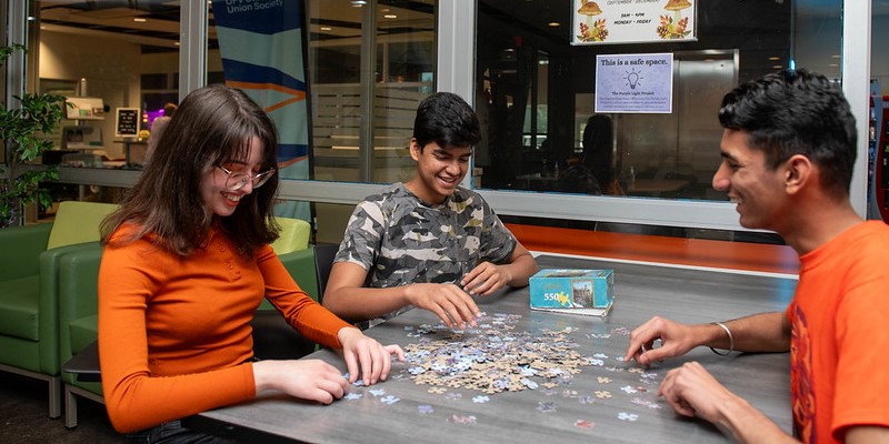 A trio of students work on a puzzle in the student lounge