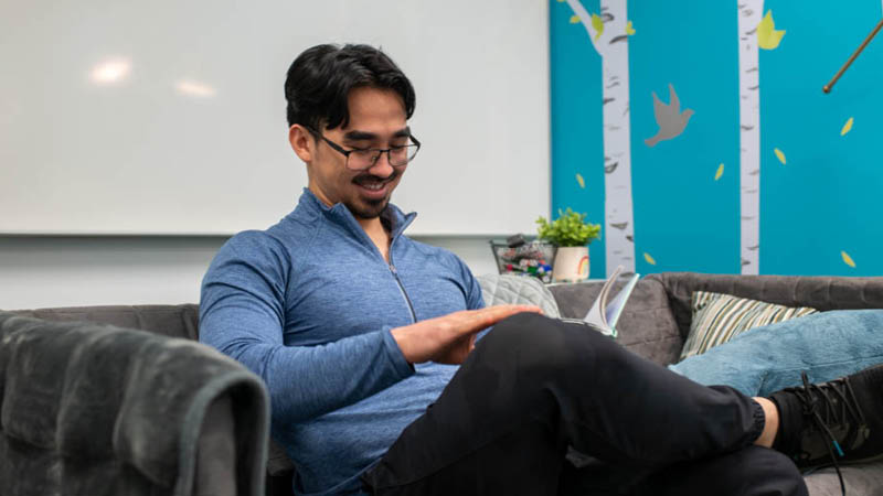 UFV student relaxes on a couch while reading a book