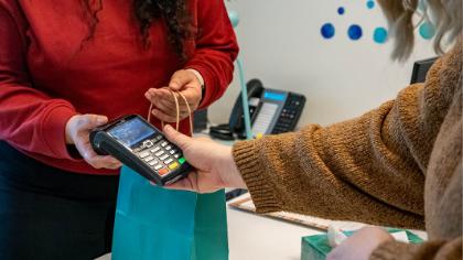 A person making payment and receiving a discreet gift bag in return.