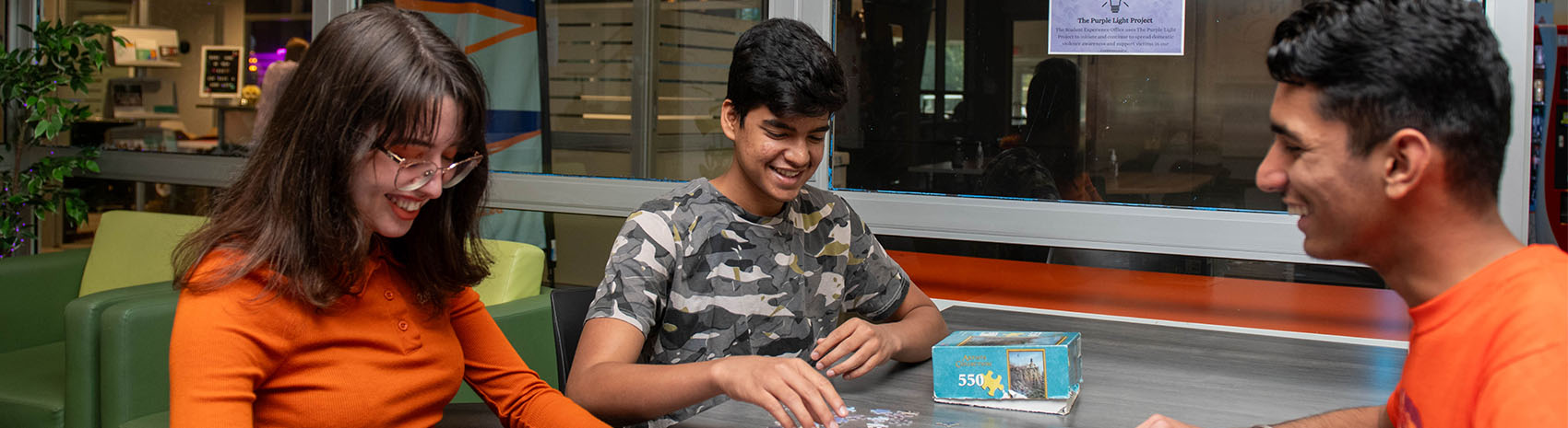 A group of students sitting at a table playing a puzzle.